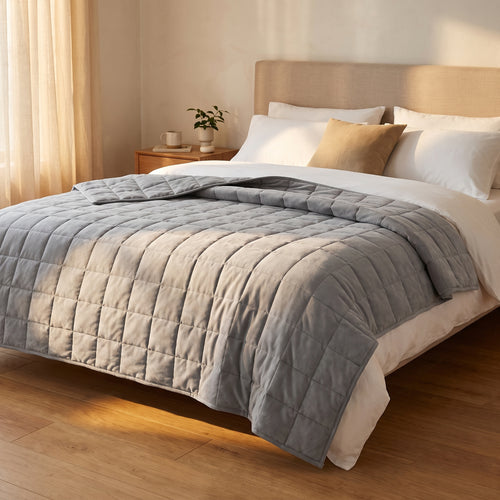 Couverture lestée Lestona, coloris gris, dépliée sur un lit dans une chambre
