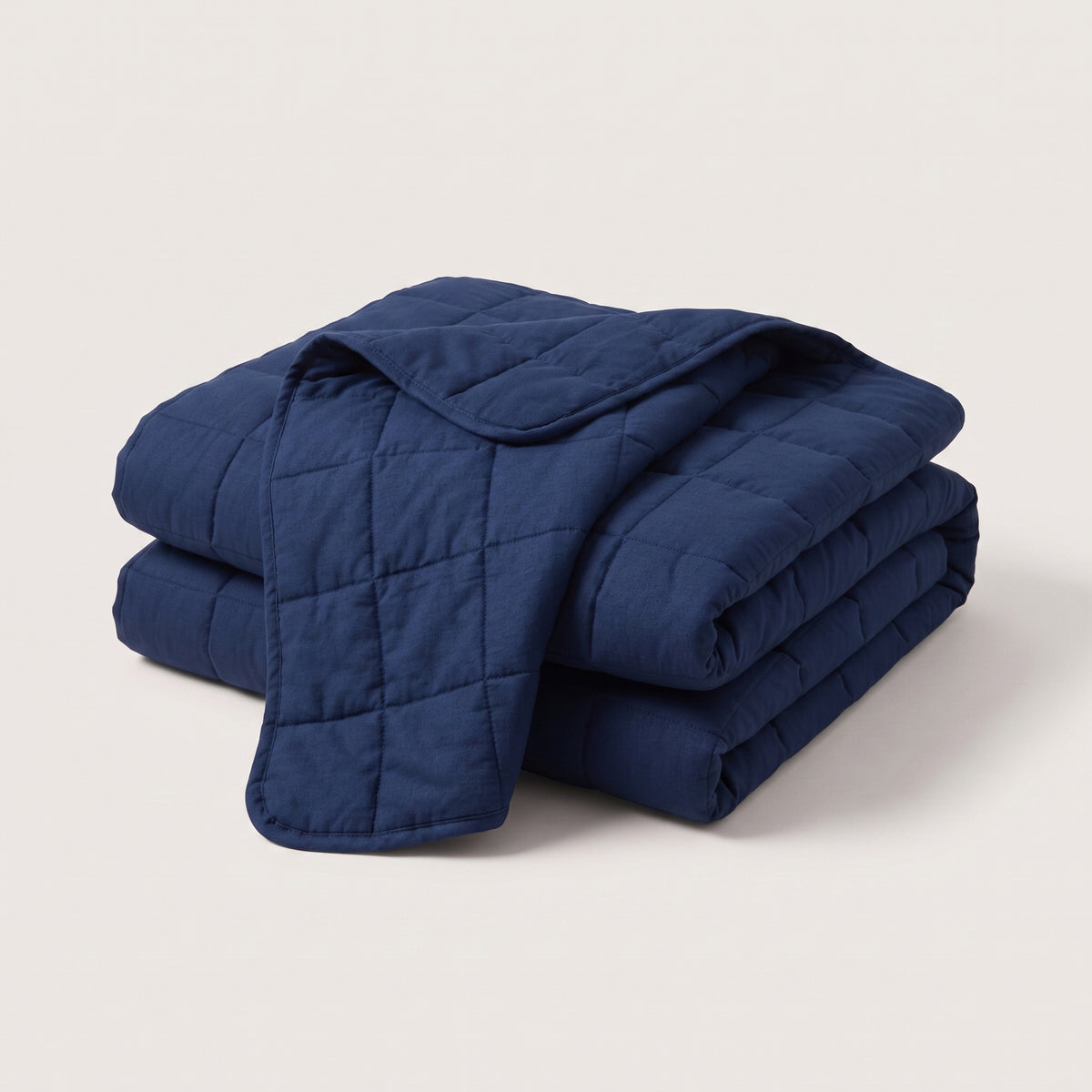 Couverture lestée Lestona pliée, coloris bleu marine, sur fond neutre.